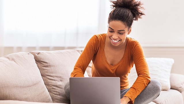 Image of a woman working on a laptop on the couch.
