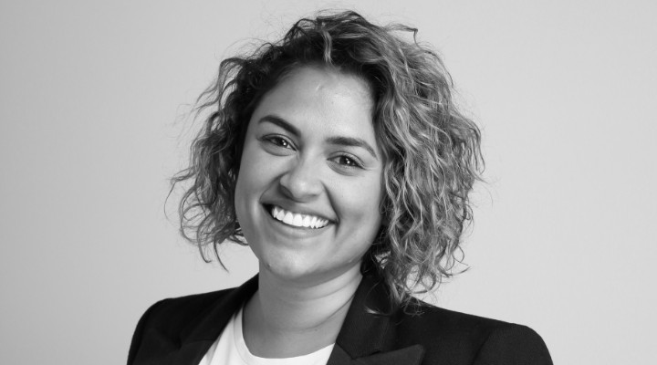 A black and white shot of Charlene Perera with short curly hair and a black blazer