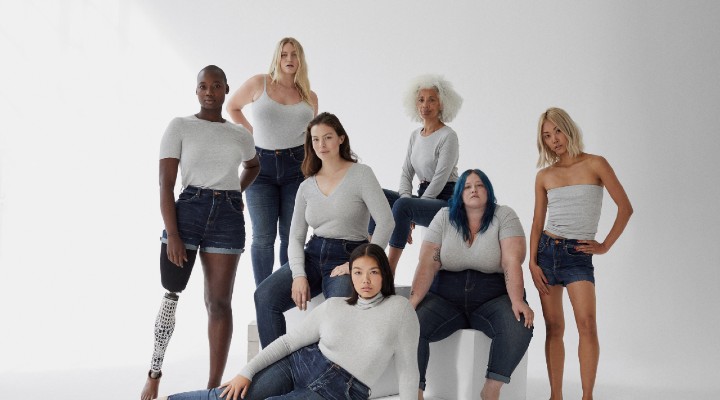 A group of diverse women with white tops and jeans on.