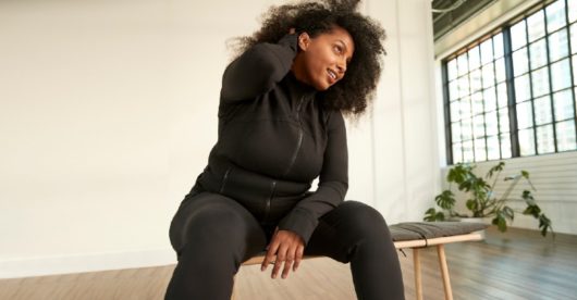 A woman in black activewear sitting on a bench
