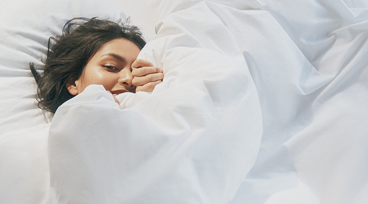A woman in bed with white sheets.
