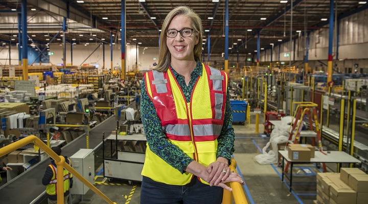 Amazon Australia boss Janet Menzies stands in a warehouse wearing a high-vis vest.