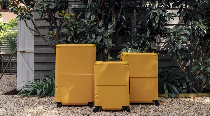 Three pieces of yellow luggage in an outdoor setting.