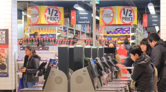 Coles price drops and customers at self checkout counters