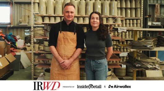 Bobby and Hannah Gordon stand in front of a rack of ceramics in the Robert Gordon factory