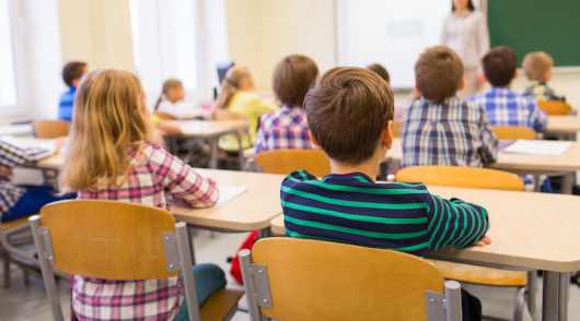 An interior shot of an elementary school classroom filled with students.
