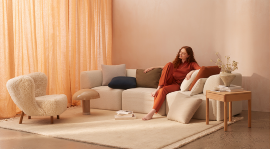 campaign image from australian furniture brand eva showing red-haired model sitting on a sofa