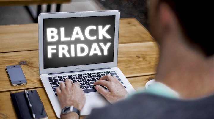 A man sitting down, typing away at a computer with “Black Friday” on the screen.