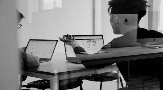 two team members working on laptops